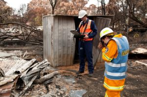 Two people in high visibility clothing standing in burnt wreckage