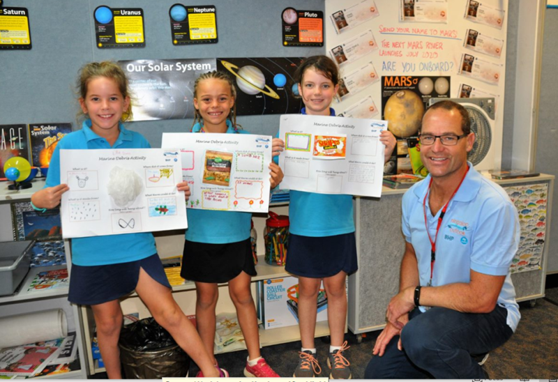 CSIRO scientist with school students from Exmouth School holding up their science activities on paper
