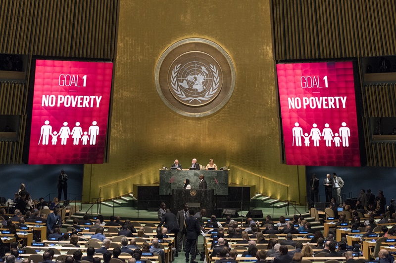 UN general assembly with two big screens either side of the podium saying Goal 1 No Poverty