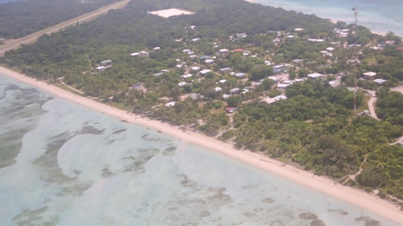 View of a narrow island from the sky with a small town and the ocean visible on both sides of the island