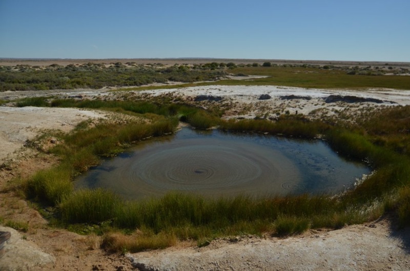 A small round pond of water in arid landscape