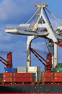 Shipping containers on a cargo vessel in front of port cranes