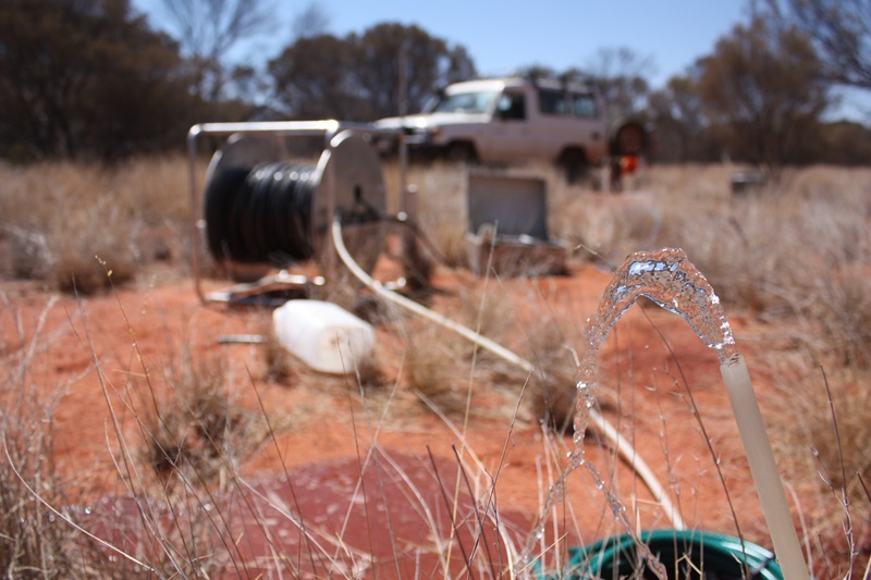 Water pouring out of a hose with outback setting in background