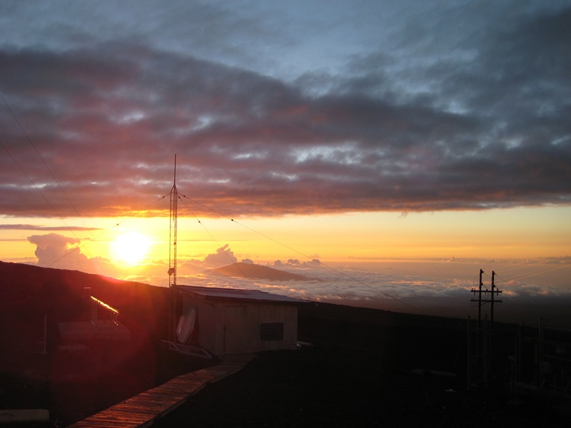 View over the observatory with sunset and mountain top poking through the clouds in background