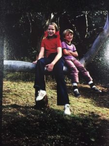 A young girl and boy sitting on a tree branch