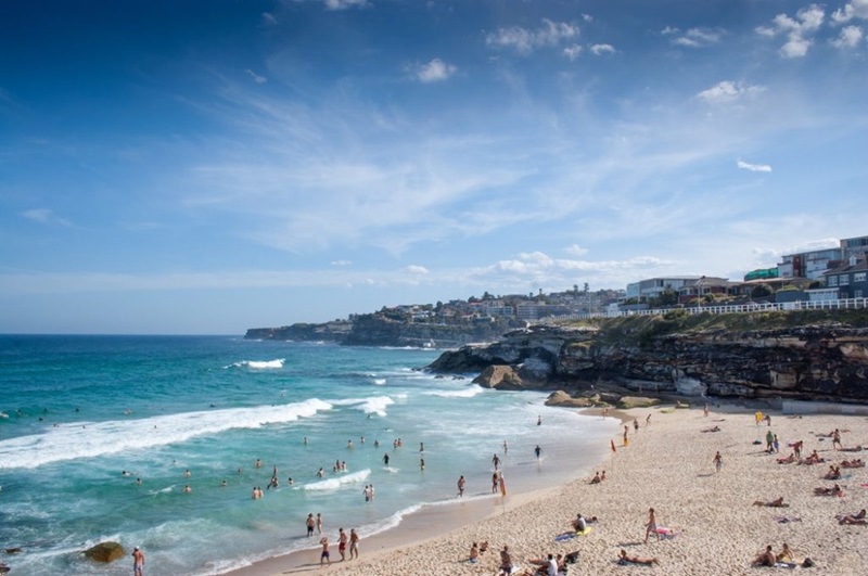Landscape shot of Bondi Beach with people on the sand and urban development in the background