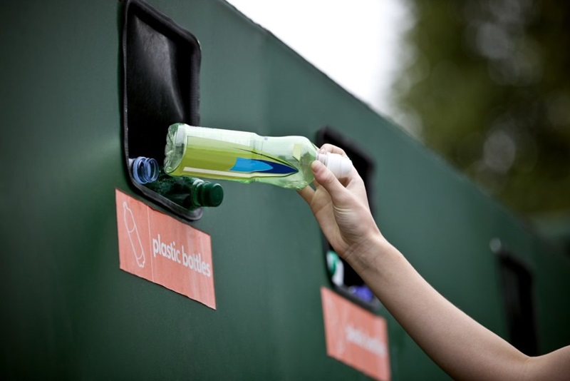 Placing a plastic bottle in a recycling bin
