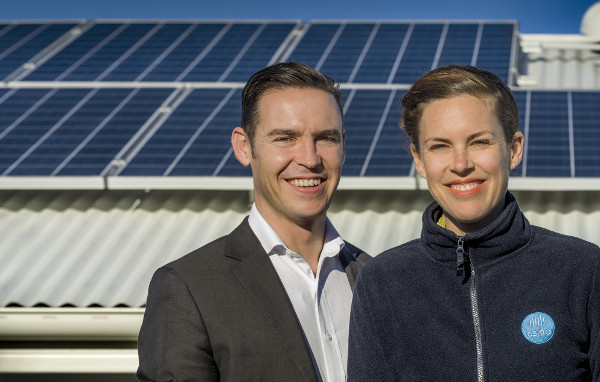 man and woman standing in front of roof with solar panels