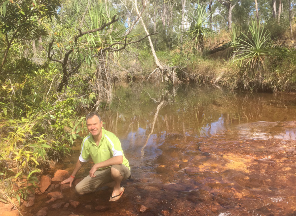 Man crouched near water hole