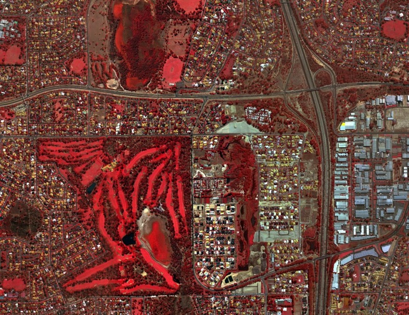 An aerial view of city streets and buildings with areas coloured in red