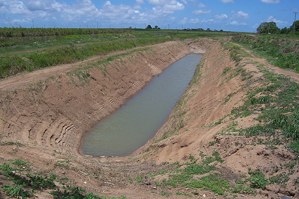 A long oval pit in a field, with water sitting in the bottom