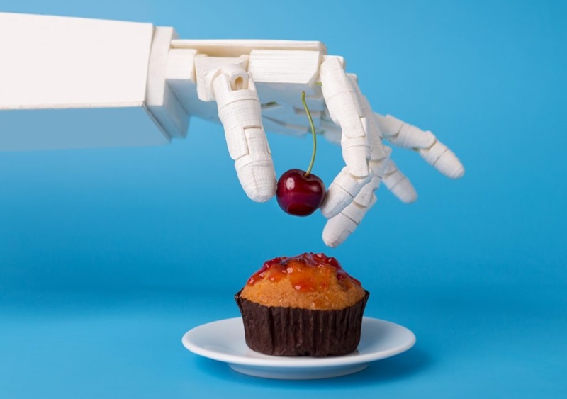 Robot hand decorating sweet cupcake with fresh cherry