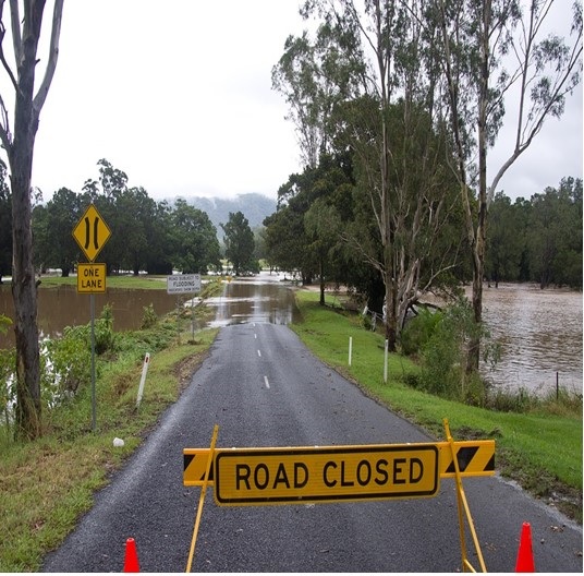 Picture of a road with a road closed sign in front due to flooding.