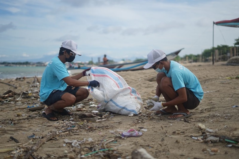 two people doing a beach clean up on a beach in Bali