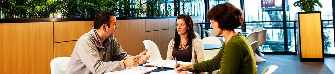 three people having a business meeting around a table.