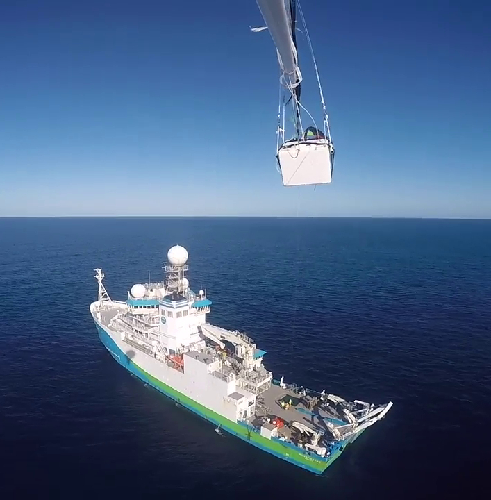 A piece of scientific equipment at the top of the image and below is a full view of the research vessel, Investigator, on the ocean.
