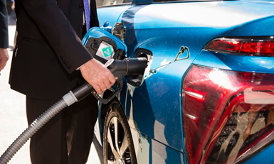 man in suit filling up hydrogen vehicle with fuel