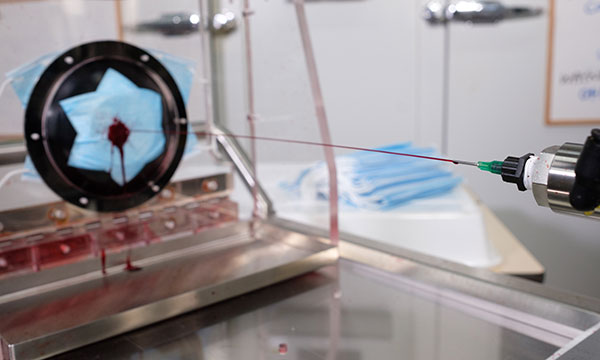 A stream of red liquid is fired at a mask
